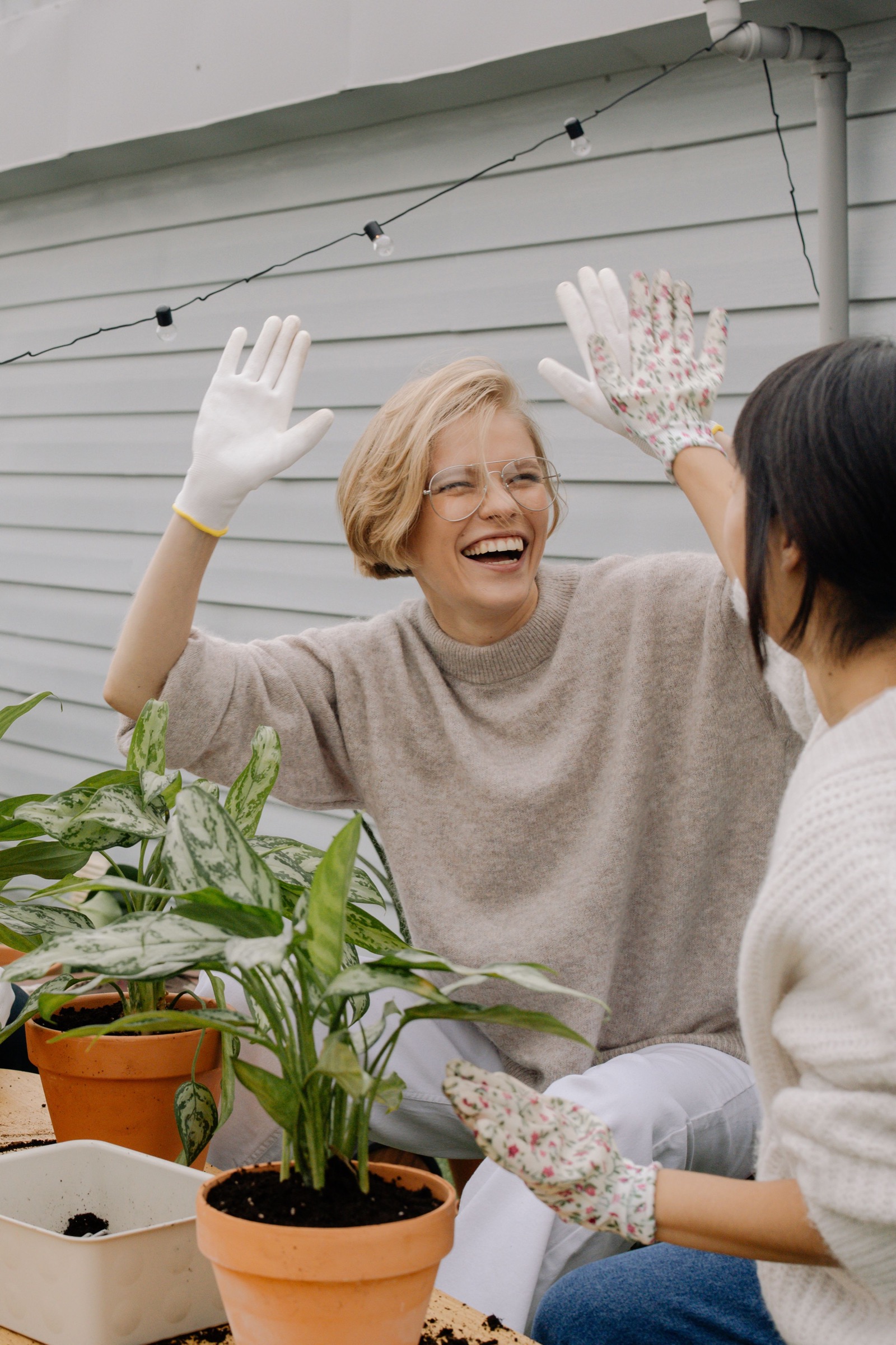 Two women laughing together while tending potted plants